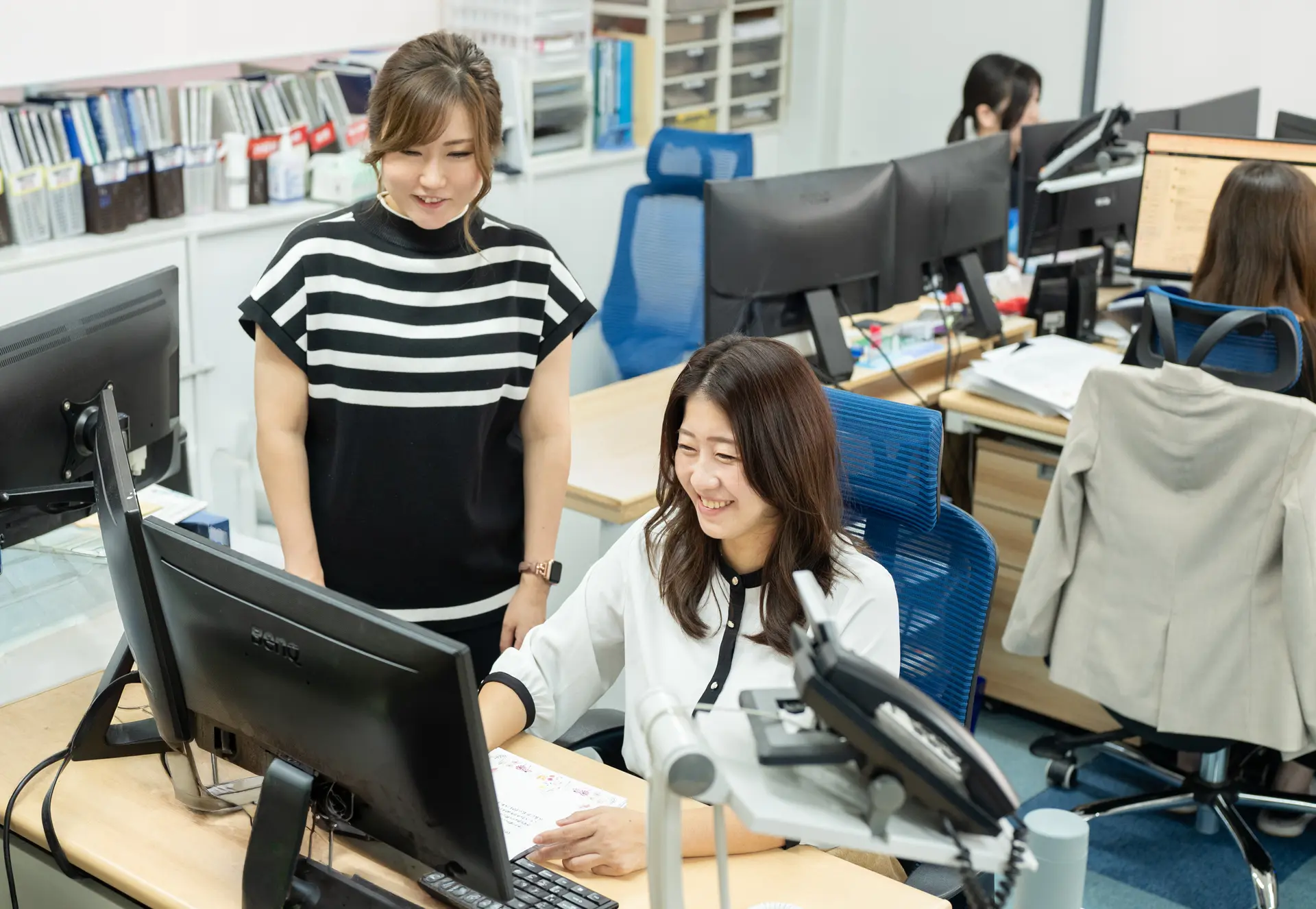 PC画面を見ながら打ち合わせしている女性社員